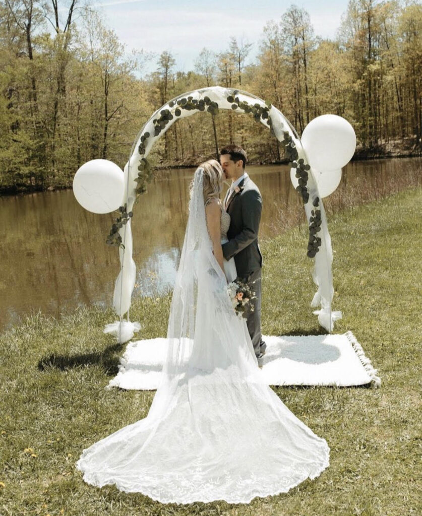 bride and groom kiss under arch